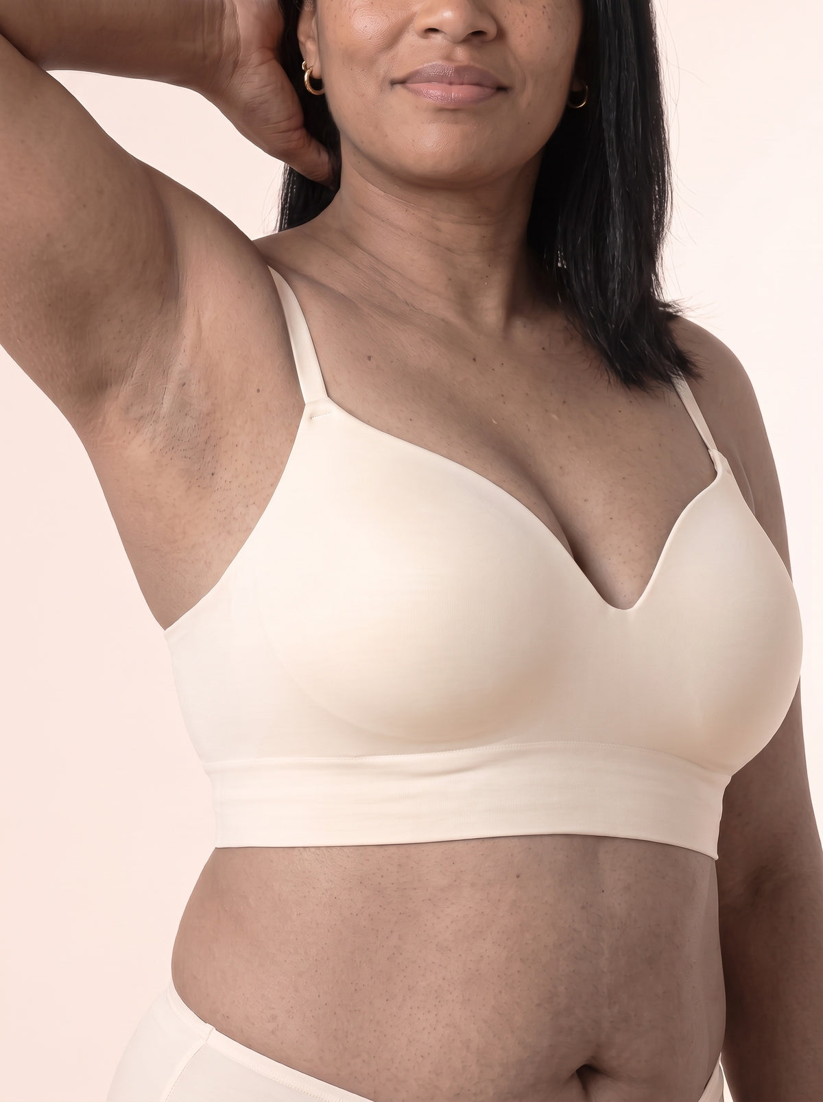 Denise raising one arm in the Chai bra — side of the cup and the wide underbust band