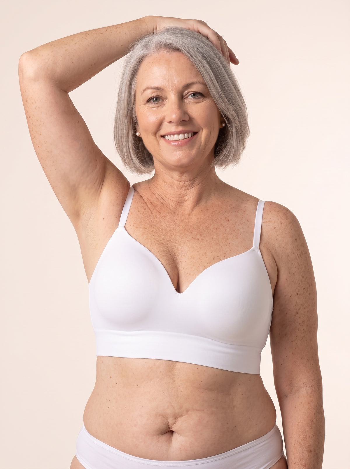 Diane, 38DD, in the Snug Wireless Shaping Bra in White — front view, one hand on her head